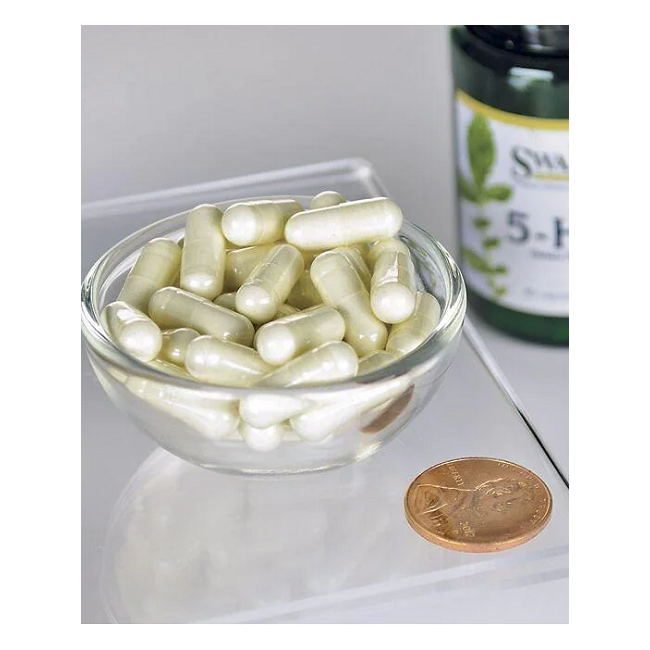 A small glass bowl of white capsules is displayed next to a penny for scale, with a Swanson 5-HTP (Hydroxytryptophan) 50 mg supplement bottle in the background. These 60 capsules are known for aiding mood regulation and enhancing serotonin levels, inviting curiosity and promising balance.