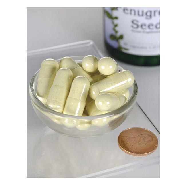 A small glass bowl filled with yellow capsules and tablets sits beside a coin for scale, while a bottle labeled "Swanson Fenugreek Seed 610 mg 90 Capsules," known for supporting blood sugar levels, is partially visible in the background.