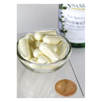 Thumbnail for A small glass bowl filled with white capsules sits on a reflective surface beside a penny, with a Swanson Boswellia 800 mg 60 Capsules bottle, known for joint health benefits in Ayurvedic tradition, in the background.