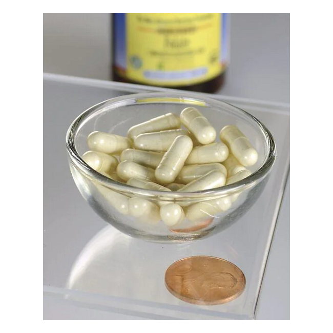 A glass bowl containing white capsules, Swanson's Folate 5-MTHF - 400 mcg, ideal for pregnancy, rests on a clear surface beside a penny, with a blurred medicine bottle in the background.