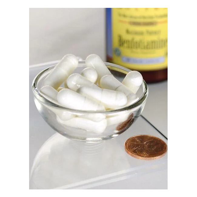 A small glass bowl contains Swanson's Benfotiamine (Vitamin B1) 300 mg veggie capsules for energy, alongside a penny for scale, with a blurred bottle in the background.