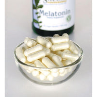 Miniatura de Swanson Melatonina - 0,5 mg 60 cápsulas vegetales en un recipiente de cristal junto a un frasco.