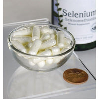 Miniatura de Swanson Selenio - 100 mcg 200 cápsulas L-Selenometionina en un cuenco junto a un céntimo, que ofrece apoyo antioxidante para la salud cardiovascular.