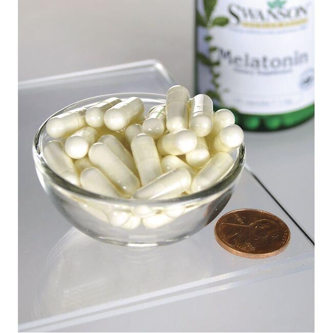 Swanson Melatonina - 1 mg 120 cápsulas en un cuenco junto a una botella de Swanson Melatonina.