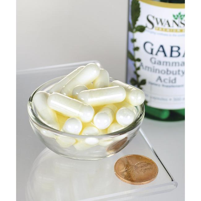 Un frasco de Swanson GABA - 500 mg 100 cápsulas y un céntimo al lado.