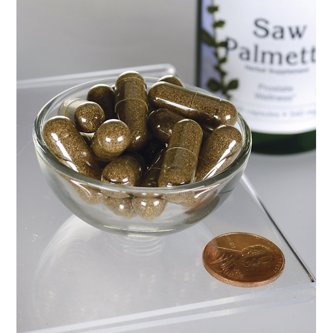 SwansonSaw Palmetto - 540 mg 100 cápsulas, un popular suplemento para la próstata, se muestran en un cuenco junto a un penique.