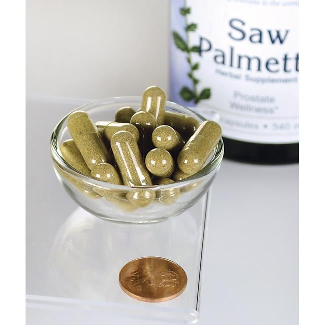 Swanson Saw Palmetto - 540 mg 250 cápsulas, conocidas por su papel en el fomento de la salud de la próstata y la fluidez de las vías urinarias, se exponen en un cuenco junto a un penique.