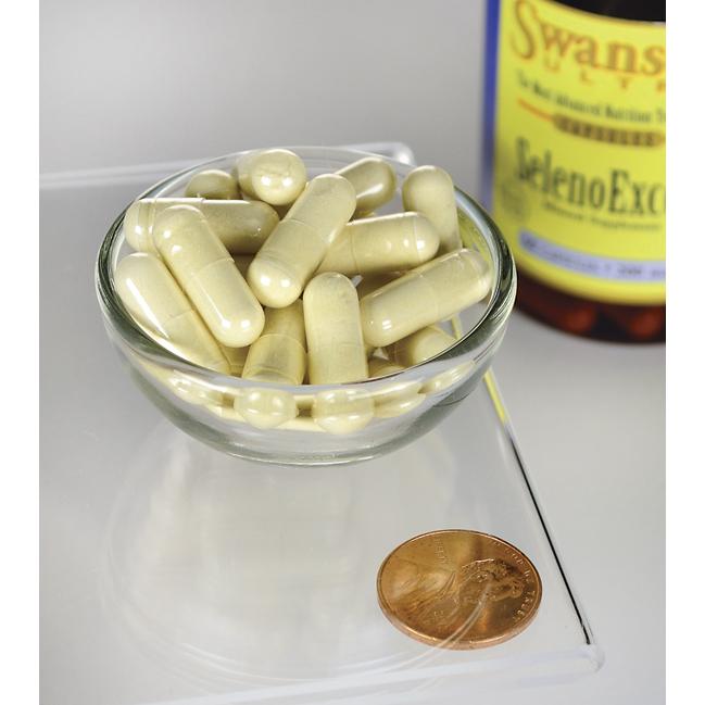 Un frasco de Swanson's SelenoExcell Selenio - 200 mcg 60 cápsulas suplementos y un céntimo junto a un bol de pastillas, promoviendo el cuidado cardiovascular.