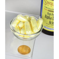 Thumbnail for Un frasco de Swanson Ácido Alfa Lipoico - 600 mg 60 cápsulas con una moneda al lado.