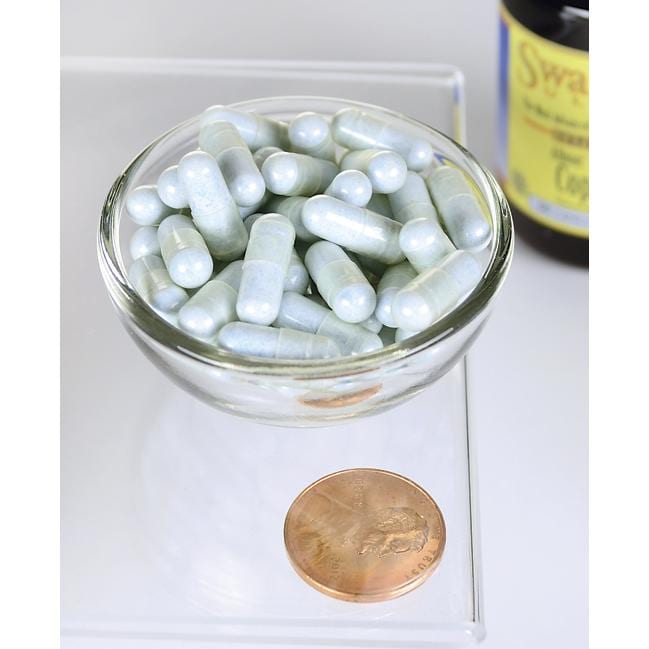 Un cuenco de Swanson Copper - 2 mg 60 capsules Albion Chelated junto a un penique.