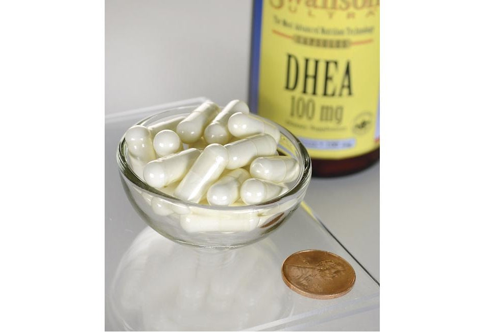 Swanson DHEA - 100 mg 60 cápsulas en un cuenco junto a un penique.