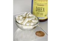 Miniatura de Swanson DHEA - 100 mg 60 cápsulas en un cuenco junto a un penique.